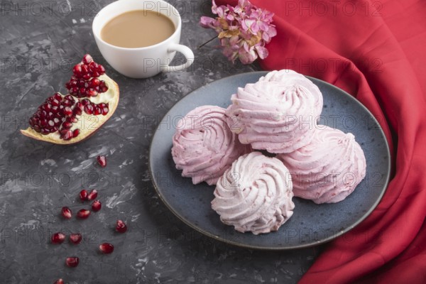 Pink pomegranate homemade zephyr or marshmallow with cup of coffee on a black concrete background with red textile. side view, close up