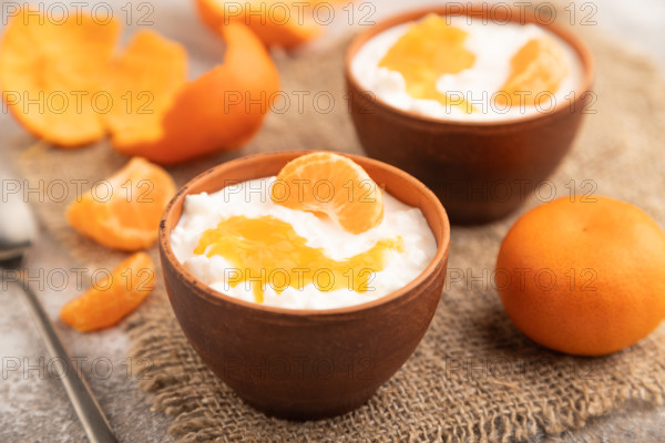 Grained cottage cheese with tangerine jam on brown concrete background and linen textile. side view, close up, selective focus