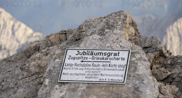 Signpost for difficult mountain tour, signpost Jubiläumsgrat in the evening light, steep rocky mountain landscape, Wetterstein range, Bavaria, Germany, Europe