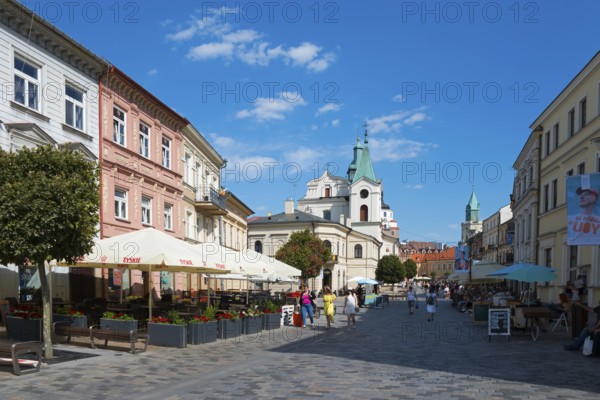 Lively historic street with church, cafés and passers-by under a blue sky, Church of the Holy Spirit, Krakowskie Przedmiescie Street, Lublin, Poland, Europe