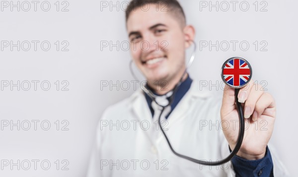 UK National Healthcare concept. Smiling doctor showing stethoscope with UK flag