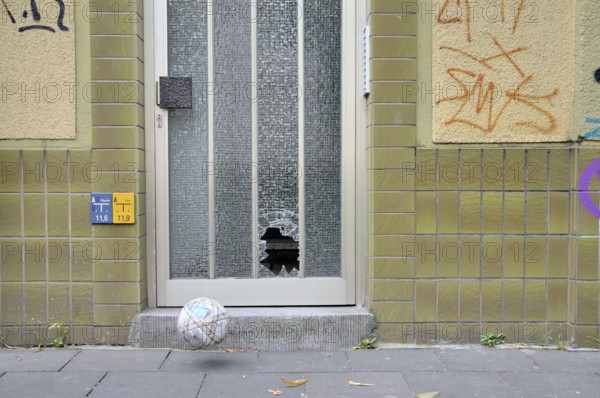 Shattered glass pane on a front door and football, Germany, Europe