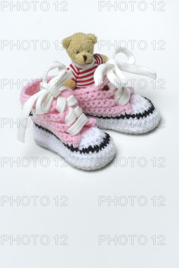 Baby shoes and teddy bear, white background