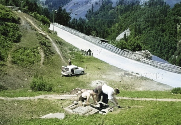 Men making tea and food, British Austin Cambridge A40 car in Austria, overland drive adventure across Europe, 1956 colourised Ektachrome slide