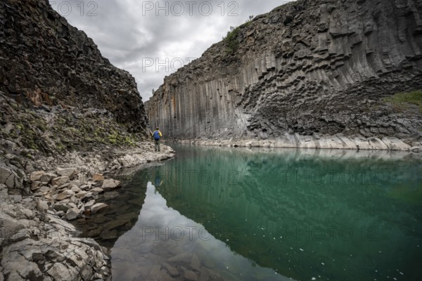 Tourist standing by the river in Stuðlagil Canyon, turquoise blue river between basalt columns, Egilsstadir, Iceland, Europe