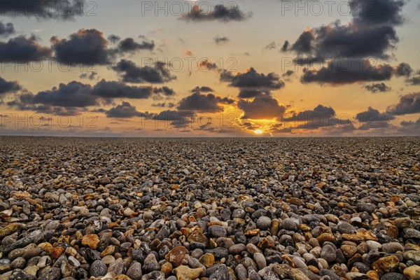 Empty pebble beach by the sea, sunset on the horizon