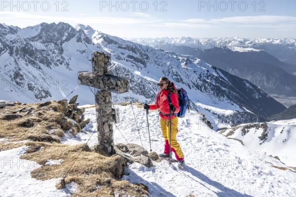 Ski tourers at the summit of the Mitterzeigerkogel with summit cross in winter, Sellraintal, Kühtai, Tyrol, Austria, Europe