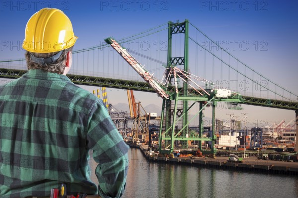 Male worker wearing yellow hard hat overlooking the san pedro ship yard and bridge