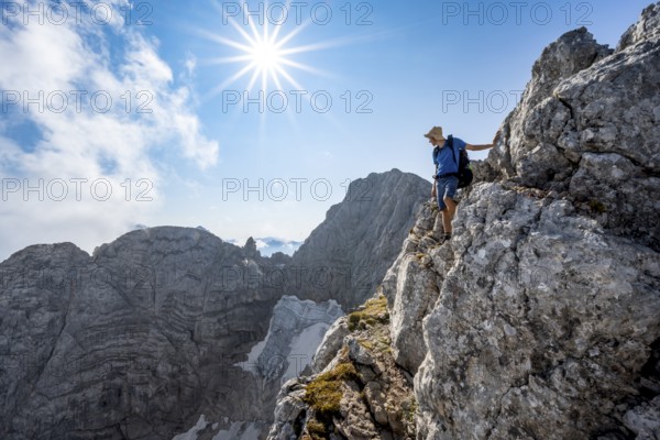 Mountaineer on a rocky narrow mountain path, view of rock faces with blue ice glacier and summit of the Hochkalter, Sonnenstern, mountain tour on the Hochkalter, Berchtesgaden Alps, Bavaria, Germany, Europe