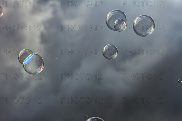 Soap bubbles iridescent, floating in front of dark clouds, wallpaper