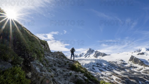 Mountaineer in front of high alpine mountain landscape with sun star, summit of Aiguille de Chardonnet and Glacier du Tour, glacier and mountain peaks, Chamonix, Haute-Savoie, France, Europe