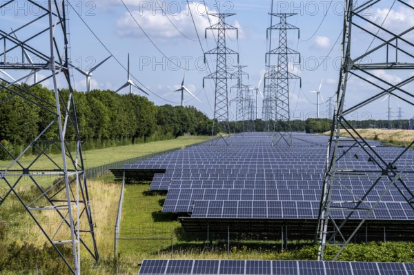 High-voltage power line route, the space underneath is used for a solar park over 5 km long, behind it a wind farm, in the harbour area of Vlissingen-Oost, Netherlands