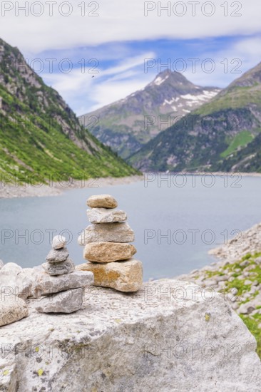 Mountain landscape with a calm lake and a pile of stones in the foreground, surrounded by green mountains, Klein Tibet, Zillertal, Austria, Europe