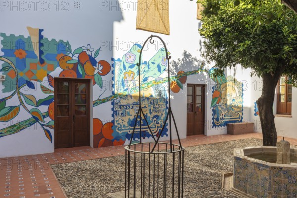 Courtyard with colourful mural and tree, warm colours and cheerful atmosphere, Cordoba