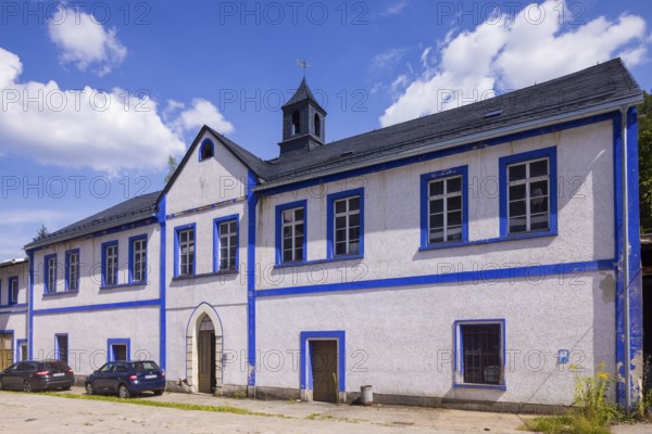 Schindler's blue colour factory is located directly on the Zwickauer Mulde and is part of the Zschorlau district of Albernau in the Saxon Ore Mountains. Since 2019, it has been part of the Schneeberg Mining Landscape and a UNESCO World Heritage Site in the Erzgebirge/Krušnohorí Mining Region. On 27 February 1649, the Schneeberg merchant Erasmus Schindler bought a plot of land to build a blue paint factory on the Zwickauer Mulde near Albernau. On 4 May 1649, he received the privilege to build a blue dye mill from Elector Johann Georg I. As Schindlerswerk GmbH & Co. KG, it is probably the world's oldest paint factory still in production. It is associated with a long tradition of producing blue cobalt pigments and the commercial manufacture of colour pigments. In more recent times, production has been expanded to include various paints. Laundry blue is also produced. Manor house and building of the packing plant, bathing plant, dispatch department, Schindlerswerk, Zschorlau OT Albernau, S...