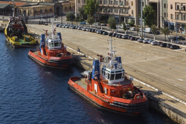 High angle view of docked orange, white and blue Capo D'Orlando and Megrez tugboats plus larger yellow and green tugboat, Port of Messina, Sicily, Italy, Europe