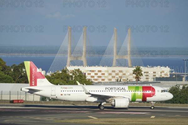 Lisbon, Portugal - September 2, 2023: TAP Air Portugal Airbus A321-251N passenger plane taxi on runway in Humberto Delgado Airport in Lisbon with Vasco da Gamma bridge in background