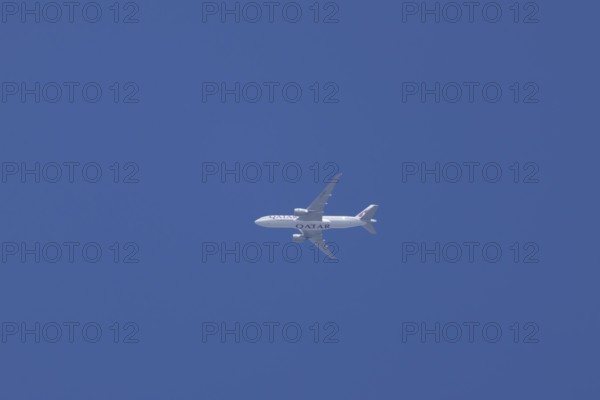 Boeing 777 jet aircraft of Qatar air cargo in flight across a blue sky, England, Unird Kingdom