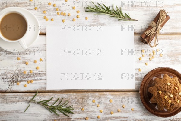 White paper sheet mockup with cup of coffee and cake on white wooden background. Blank, top view, flat lay, still life