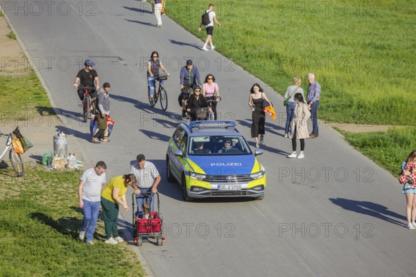 Groups of men out and about on the banks of the Elbe, the Elbe cycle path and the Elbe meadows. A police patrol car on the Königsufer, Dresden, Saxony, Germany, Europe