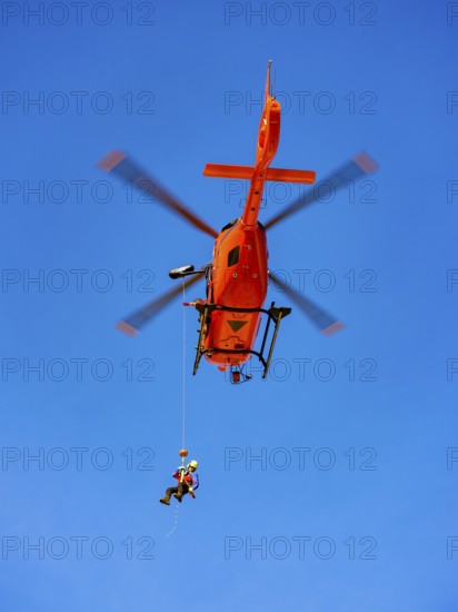 Mountain rescuer of the Bavarian Mountain Rescue Service being winched by the on-board mechanic of the rescue helicopter Christoph 14 with the cable winch, Bad Reichenhall, Berchtesgadener Land, Upper Bavaria, Bavaria, Germany, Europe