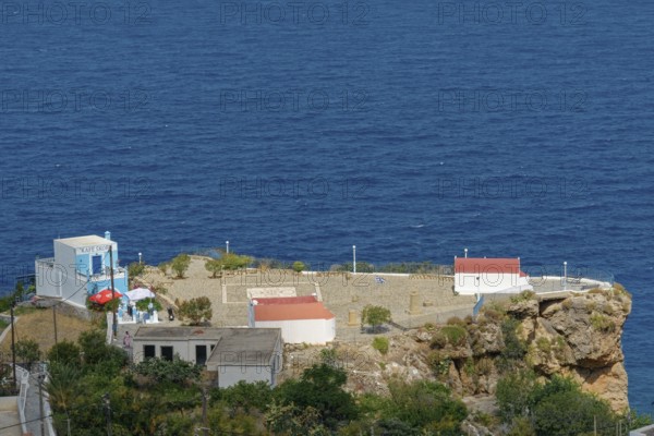 Platia Skopi with Kafe Skopi on a rocky cliff overlooking the deep blue sea and clear sky, Mesochori, Karpathos, South Aegean, Greece, Europe