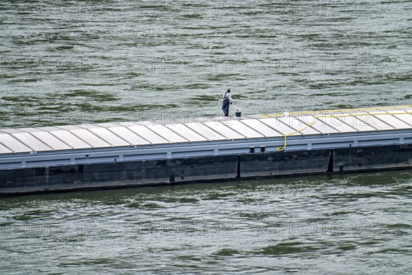 Inland waterway vessel, freighter, with closed cargo hatches, employee cleans the deck with water and scrubbing brush, on the Rhine, Rhineland-Palatinate, Germany, Europe