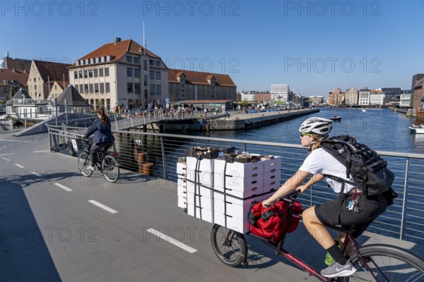 Cyclists on the Inderhavnsbroen cycle and footpath bridge, over the harbour, at Nyhavn, Copenhagen is considered the cycling capital of the world, 45 % of the population travel by bike, Denmark, Europe