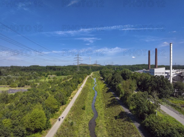 Bottrop, North Rhine-Westphalia, Germany, Renaturalised Boye, the tributary of the Emscher, was transformed into a near-natural watercourse, flood protection through newly designed floodplains, the Boye is now free of wastewater after the construction of a parallel sewer, is part of the Emscher river system and thus part of the Emscher conversion, was previously an open, above-ground wastewater channel, mixed water channel with surface water and wastewater. Wind turbine on the Mottbruch spoil tip at the back. On the right, industrial area with chimneys in the city of Essen, Europe