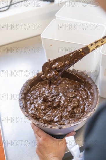 Hand holding a bowl of melted chocolate and stirring it, Burch Schokolade production, Haselstaller Hof, Gechingen, Germany, Europe