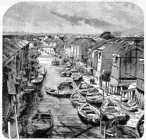 Wooden houses and sandy paths along a canal in old Tokyo, many rowing boats for transporting people of goods, pedestrian bridge, Japan, historical illustration 1882, Asia