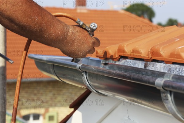 Roofer doing tinsmith work on a gutter