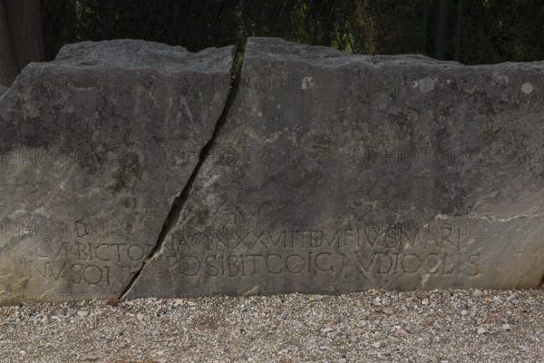 Close-up of carved letters on broken split in two large and heavy block of old weathered limestone at ancient 3rd century Roman ruins of Salona near Solin, Croatia, Europe