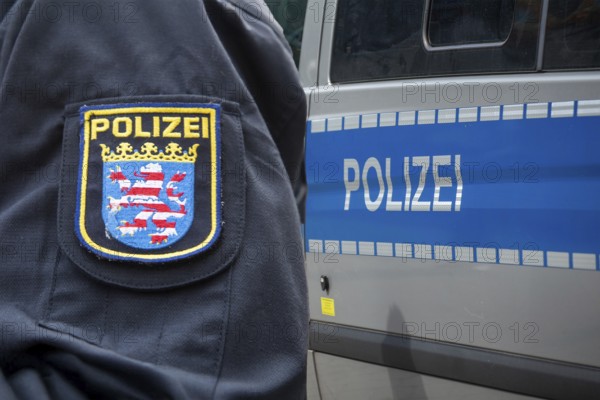 Symbolic image of a police operation in Hesse: Police officer of the Hessian police in front of an emergency vehicle (Composing)