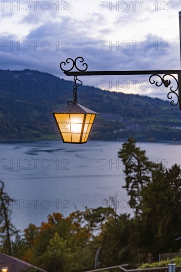 A glowing lantern with a view of a lake in a mountainous landscape, St. Beatus Caves, Switzerland, Europe