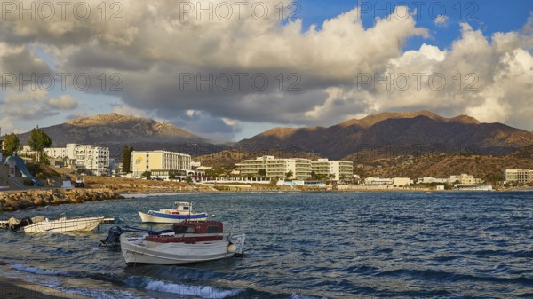 Coastal landscape with calm water, docked boats and mountains in the background, under a cloudy sky, boats, hotels, Pigadia, town and harbour, Pigadia Bay, main town, Karpathos, Dodecanese, Greek Islands, Greece, Europe