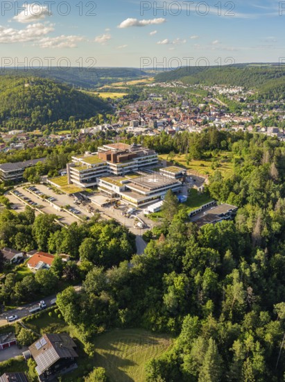 Aerial view of a town in green surroundings, many houses and a large building on a hill, blue summer sky, hospital, Nagold, Black Forest, Germany, Europe