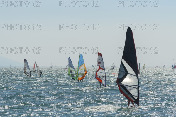 People windsurfing on a sunny day with clear blue skies and mountain backdrop, Lake garda, Torbole, Lake garda, Lago di Garda, Trentino, Italy, Europe