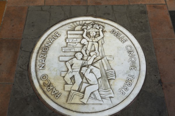 Round white marble plaque inscribed with the Italian words Parco Nazionale Delle Cinque Terre inlaid in paving stones, Manarola, Cinque Terre, La Spezia province, Italy, Europe