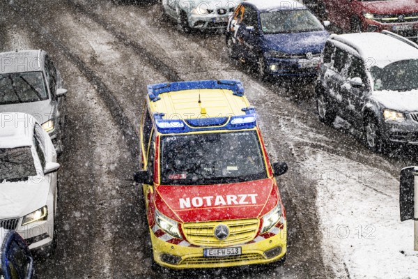 Winter weather, heavy snowfall, city centre traffic, emergency doctor vehicle of the Essen fire brigade on an emergency drive with flashing blue lights, North Rhine-Westphalia, Germany, Europe