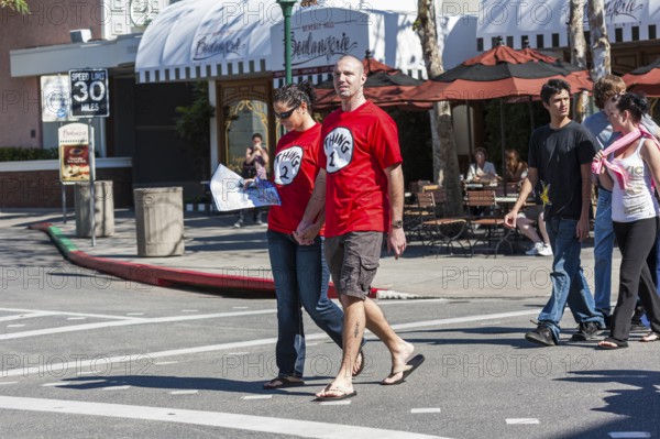 Young couple wearing Thing 1 and Thing 2 t-shirts walking on street in Universal Studios, Orlando, Florida, USA, North America