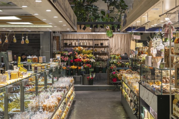 Various market stalls with floristry and delicatessen products from different nations in the historic market hall in Stuttgart, Baden-Württemberg, Germany, Europe