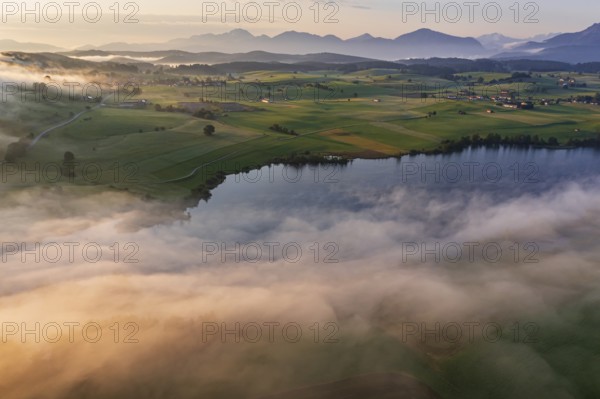 Aerial view of a lake in front of mountains in the morning light, fog, autumn, Riegsee, view of Benediktenwand and Joch, Alpine foothills, Upper Bavaria, Bavaria, Germany, Europe