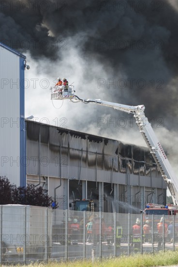 Firefighters, two firefighters with protective clothing and gas masks in aerial work platform, lifting platform on crane, smoke cloud of a large fire in an industrial building, Lower Saxony, Germany, Europe