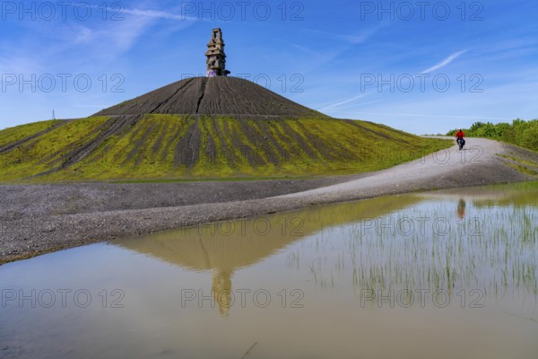 Cyclist on the Rheinelbe spoil tip in Gelsenkirchen, 100 metre high spoil tip, landscape park, with the sculpture Himmelsleiter, made of concrete parts of the former Rheinelbe colliery, Gelsenkirchen, North Rhine-Westphalia, Germany, Europe