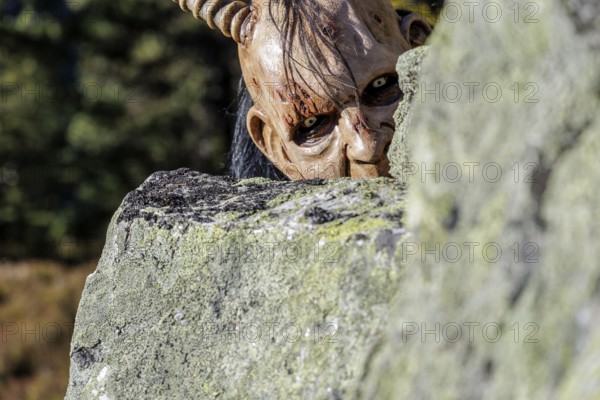 Devilish mask with horns looks out from behind a rock, Neukirchen am Großvenediger, Salzburg, Austria, Europe