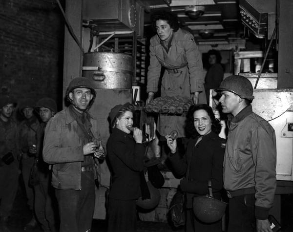 La Croix-Rouge américaine sert des doughnuts (beignets) aux soldats américains en France. (10 décembre 1944)