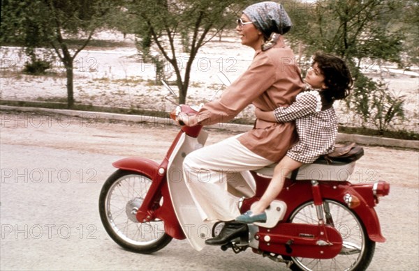 Farah Pahlavi and her daughter Leila, riding a moped (1975)