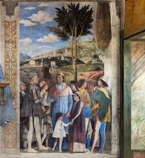 Ducal Palace: south-west wall of the “Bridal Chamber or Camera Picta", which is a room located in the north-east tower of the Castle of San Giorgio in Mantua. It is famous for the cycle of frescoes that covers its walls, a masterpiece by Andrea Mantegna, created between 1465 and 1474.
The wall, on the theme of “The Meeting” is divided into three sectors. In the one on the left the actual meeting takes place, in the central one some cherubs hold a dedicatory plaque and in the one on the right the marquis's court parades.
Detail of the right part of the wall.
The Marquis Ludovico is represented in the Meeting, this time in official guise, perhaps flanked by Ugolotto Gonzaga, son of his deceased brother Carlo. His son Francesco who is a Cardinal is in front of him. Below them are the sons of Federico I Gonzaga, Francesco and Sigismondo, while their father Federico is on the far right: the generous folds of his dress are a ploy to hide his kyphosis. Federico is in conversation with two ...