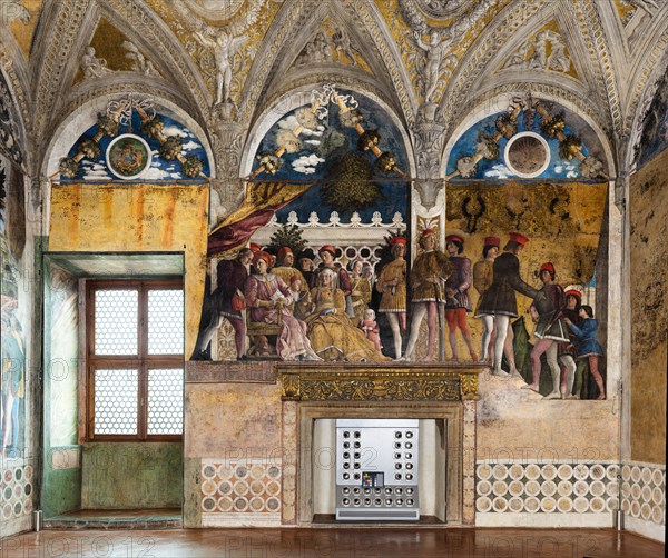 Ducal Palace: north-west wall of the “Bridal Chamber or Camera Picta", which is a room located in the north-east tower of the Castle of San Giorgio in Mantua. It is famous for the cycle of frescoes that covers its walls, a masterpiece by Andrea Mantegna, created between 1465 and 1474.
This wall represents “The Court” of Ludovico II Gonzaga. On the left, under the opened curtain, Ludovico sits while a secretary (perhaps Marsilio Andreasi or Raimondo Lupi di Soragna) hands him a letter. We see Rubino, Marquis Ludovico's favorite dog and symbol of loyalty, crouching. To her right, the only other person seated, is the Marquis's wife, Barbara of Brandenburg with a little girl, perhaps the youngest daughter Paola who seems to be offering her an apple. Behind Ludovico we can recognize the third-born Gianfrancesco standing, holding his hands on the shoulders of a child, perhaps the prothonotary Ludovicino. The man with the black hat is Vittorino da Feltre, tutor of the marquis and his childre...